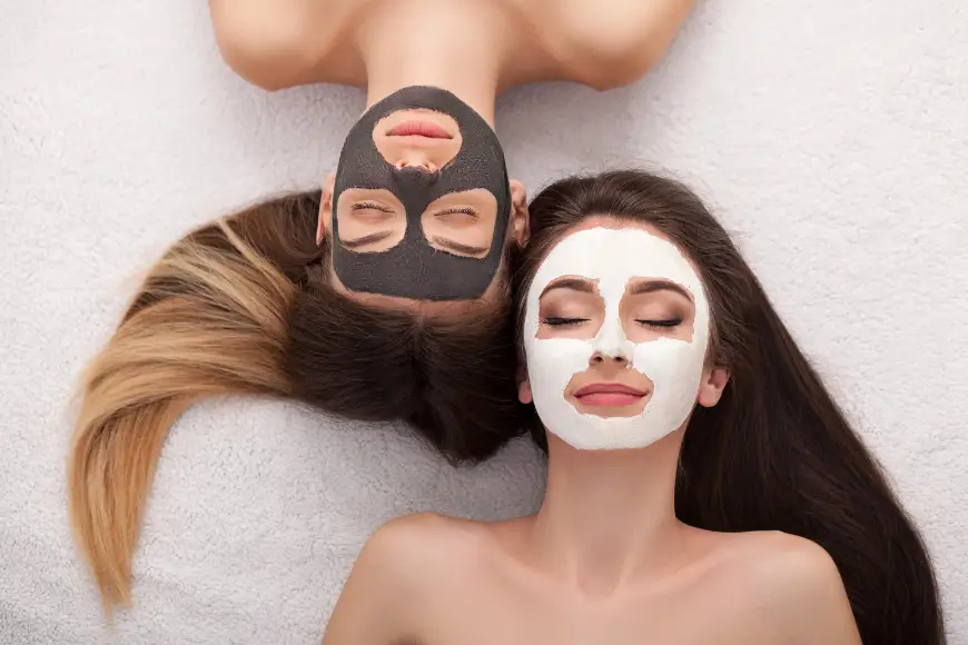 Two woman laying down with facial masks on and eyes closed while getting facials